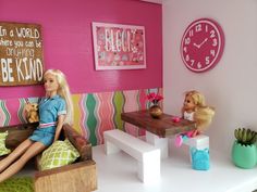 two barbie dolls are sitting on a couch in a room with pink walls and green rugs