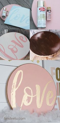 some pink and gold painted signs on the side of a wooden table with other items