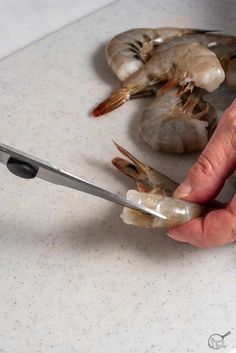 a person cutting up some shrimp with a pair of scissors on a counter top next to them