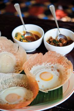 some food is sitting on a plate with bowls and spoons next to each other