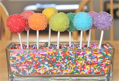 colorful sprinkles are arranged on top of cake pops in a glass container