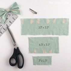 the scissors are next to two pieces of fabric with numbers on them and one piece of tape