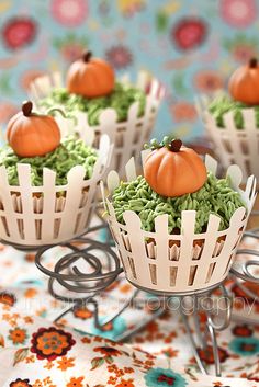 some cupcakes with green and orange frosting on them are sitting on a table