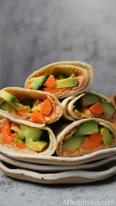 a stack of tortillas with carrots and cucumbers on them sitting on top of each other