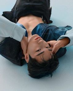 a young man laying on the ground with his head down and one hand up to his chest