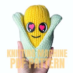 a hand holding a knitted banana toy with eyes and arms in the shape of a heart