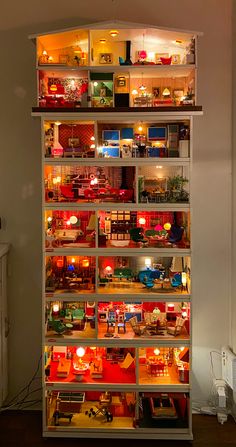 a doll house is lit up in the middle of a room with lots of furniture