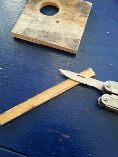 a pair of scissors sitting on top of a blue table next to a piece of wood