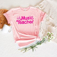 Music Teacher T-Shirt, Music Teacher Shirt, Music Educator, Musician Shirt, Singer Shirt Are you the next Music Teacher Barbie? Look the part in this pink music teacher t-shirt! Whether you're conducting a symphony, teaching an instrument, teaching an Orff arrangement, or just jamming with your friends, this Barbie-inspired tee is sure to get the show started. Get ready to hit all the right notes! This T-Shirt is super comfy, unisex sizing and the Music Teacher design is screen printed with vibr Music-themed Letter Print T-shirt For All Genders, Summer Music-themed Fitted T-shirt, Music-themed Letter Print T-shirt, Fitted Music-themed T-shirt For Summer, Music-themed Fitted Cotton T-shirt, Fitted Music-themed Summer T-shirt, Fitted Cotton Music-themed T-shirt, Cotton Music-themed T-shirt With Text Print, Unisex Short Sleeve Music-themed Top