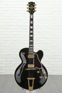 an electric guitar sitting on top of a wooden floor next to a white brick wall