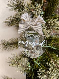 a christmas ornament hanging from a tree with the words our first christmas engaged