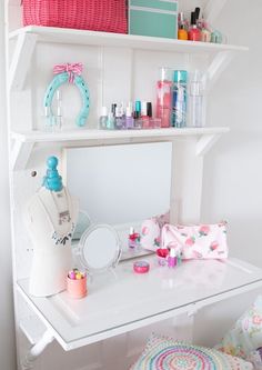 a white desk topped with lots of crafting supplies next to a wall mounted shelf