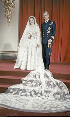 an old photo of a bride and groom standing on the steps in front of a red curtain