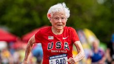 an older woman running in a race wearing a usa t - shirt and red shorts