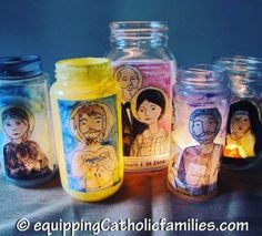 some jars with pictures on them are sitting on a table and one is filled with candles