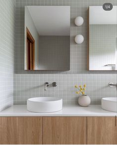 two white sinks in a bathroom under a large mirror and light wood cabinets with mirrors above them