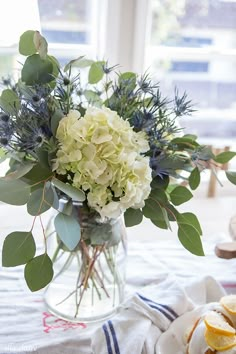 a vase filled with white flowers and greenery on top of a table next to lemon slices