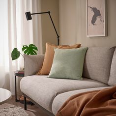 a couch with several pillows on it and a lamp in the corner next to it