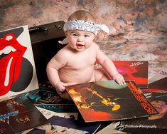 a baby sitting on top of a pile of records