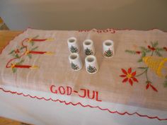 a table topped with three white vases sitting on top of a wooden tablecloth