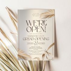 an open grand opening party with palm leaves and gold foil on the front, white background