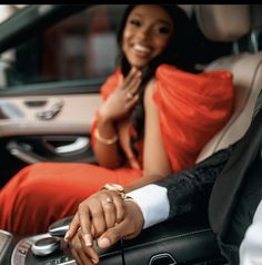 a man and woman sitting in the back seat of a car holding hands with each other