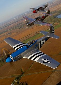 four planes flying in the sky over an open field