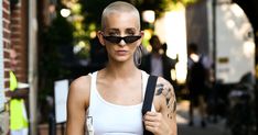 a woman with shaved hair and sunglasses on walking down the street