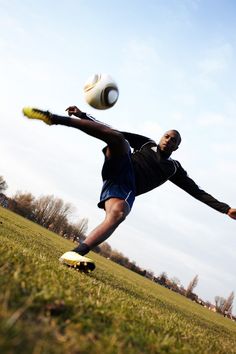 a man kicking a soccer ball on top of a field