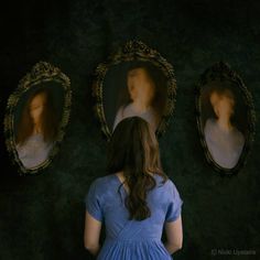 a woman standing in front of three oval mirrors with portraits on the wall behind her