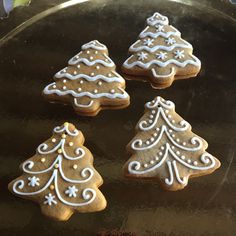 four decorated cookies in the shape of christmas trees