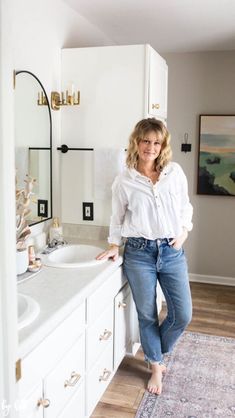 a woman standing in front of a bathroom sink