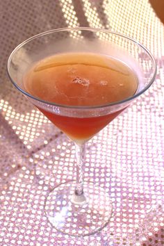 a glass filled with liquid sitting on top of a table next to a white cloth