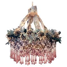 a chandelier with flowers and leaves hanging from it's sides on a white background