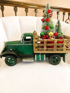 a green toy truck with a christmas tree in the back and decorations on the bed