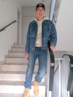 an older man standing on the stairs with his hands in his pockets and looking at the camera