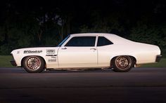 a white muscle car parked on the street at night