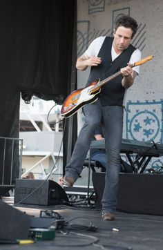 a man standing on top of a stage holding a guitar