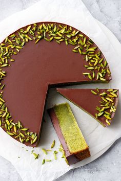 there is a chocolate cake with pistachios on the top and one slice missing