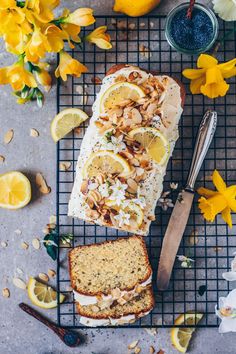 a loaf of lemon almond bread sitting on top of a cooling rack next to sliced lemons