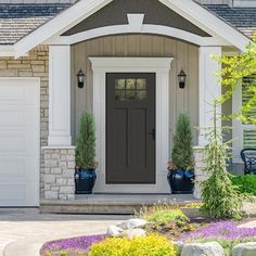 the front door of a house with two planters on it's side and flowers in pots at the entrance