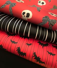 three halloween themed wrappings are stacked on top of each other, one with a skull and the other with bats