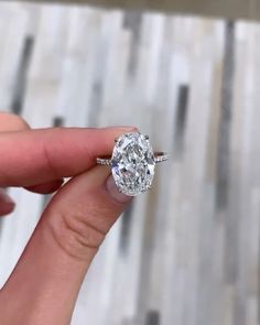 a woman's hand holding an oval diamond ring