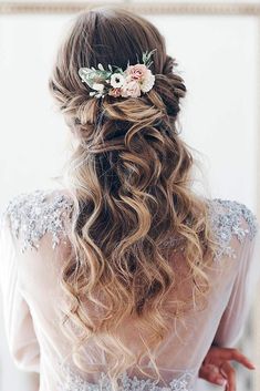 the back of a woman's head with long hair and flowers in her hair