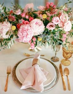 the table is set with pink flowers and gold cutlery, along with silverware