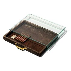 an old wooden box filled with cigars on top of a white surface and glass lid