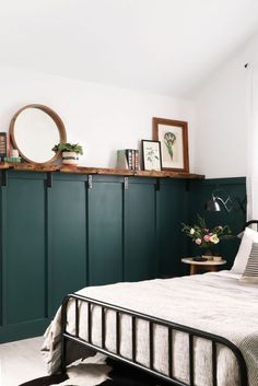 a bedroom with dark green painted walls and white bedding, along with bookshelves