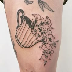 a woman's thigh with flowers and a teapot tattoo on it