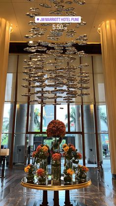 a hotel lobby with chandelier and flowers in vases on the center table