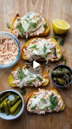 several different types of food on bread with pickles, lemons and dill